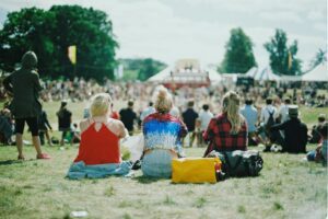 Three people sitting with their backs to the camera at a festival