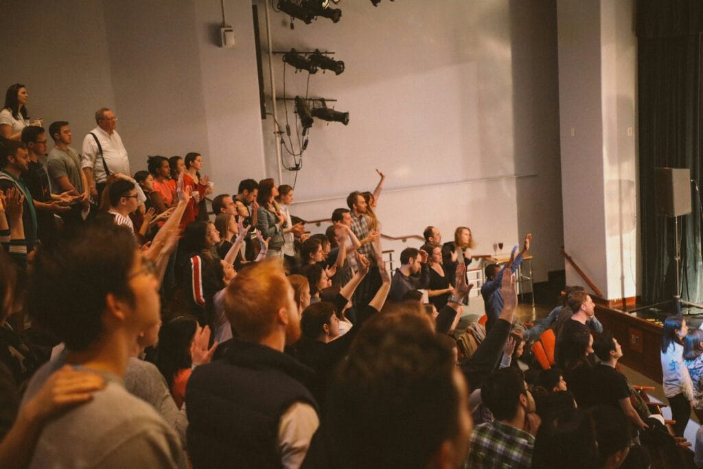 Group of people in a lecture hall with hands raised