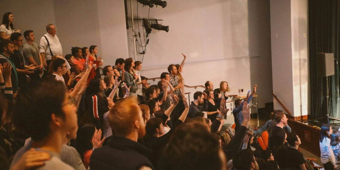 Group of people in a lecture hall with hands raised